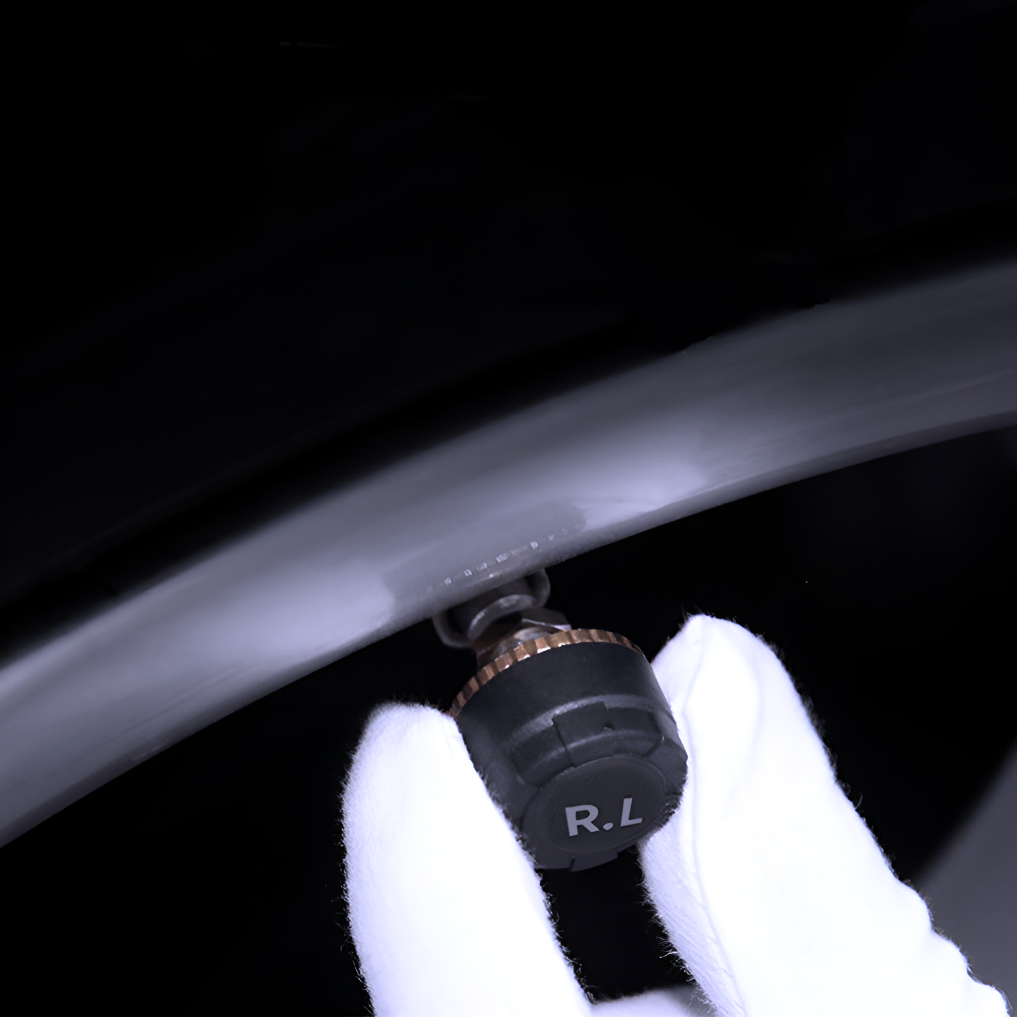 Close-up of a gloved hand using a tire pressure gauge on a car tire.