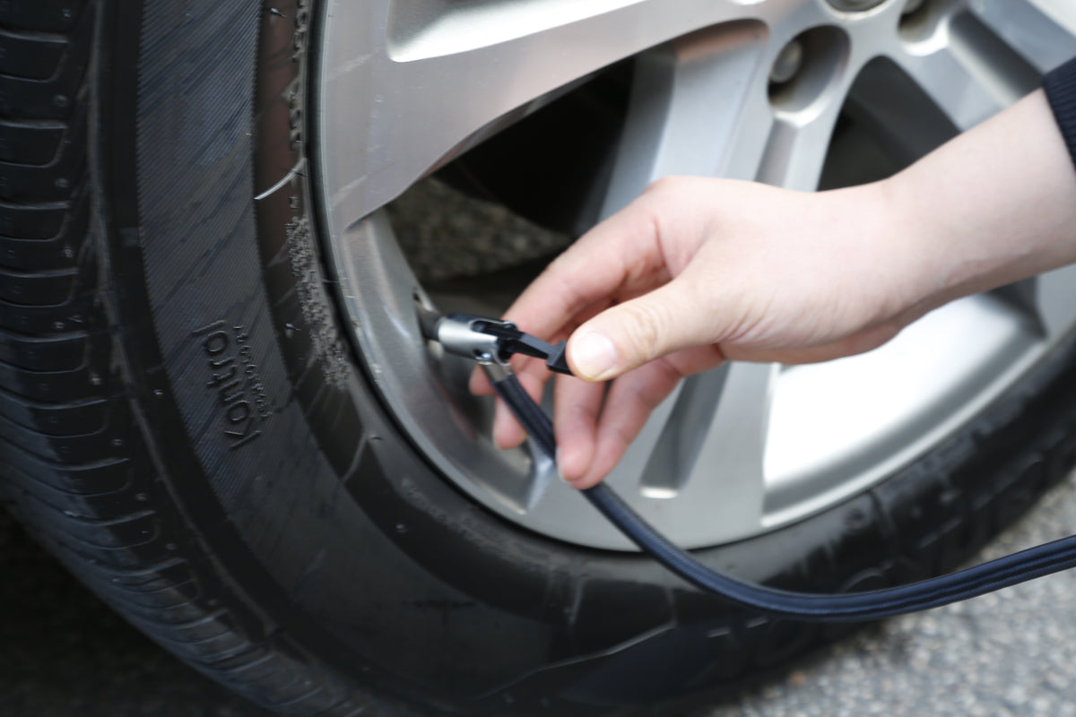 Hand using a tire inflator on a car tire