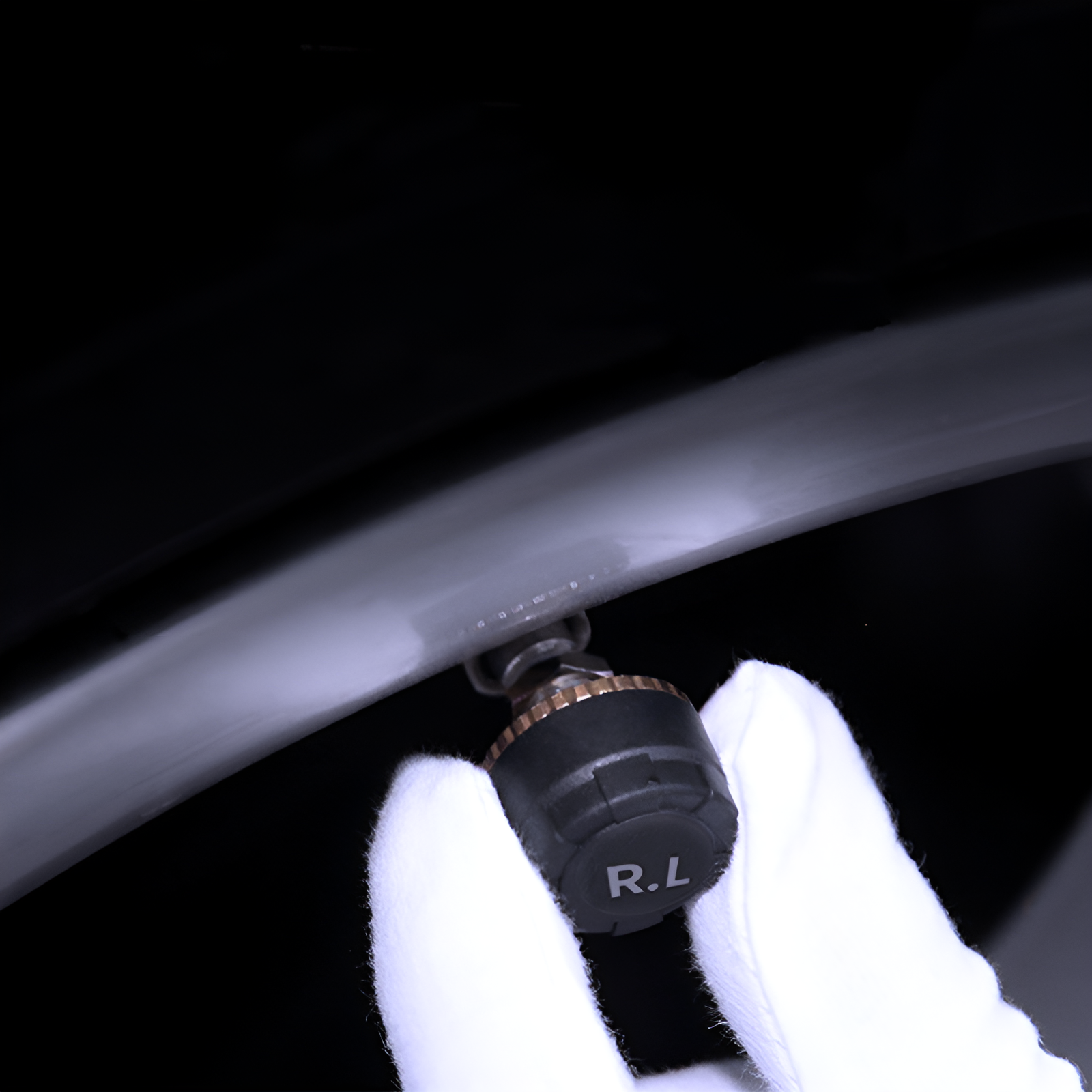 Close-up of a gloved hand using a tire pressure gauge on a car tire.