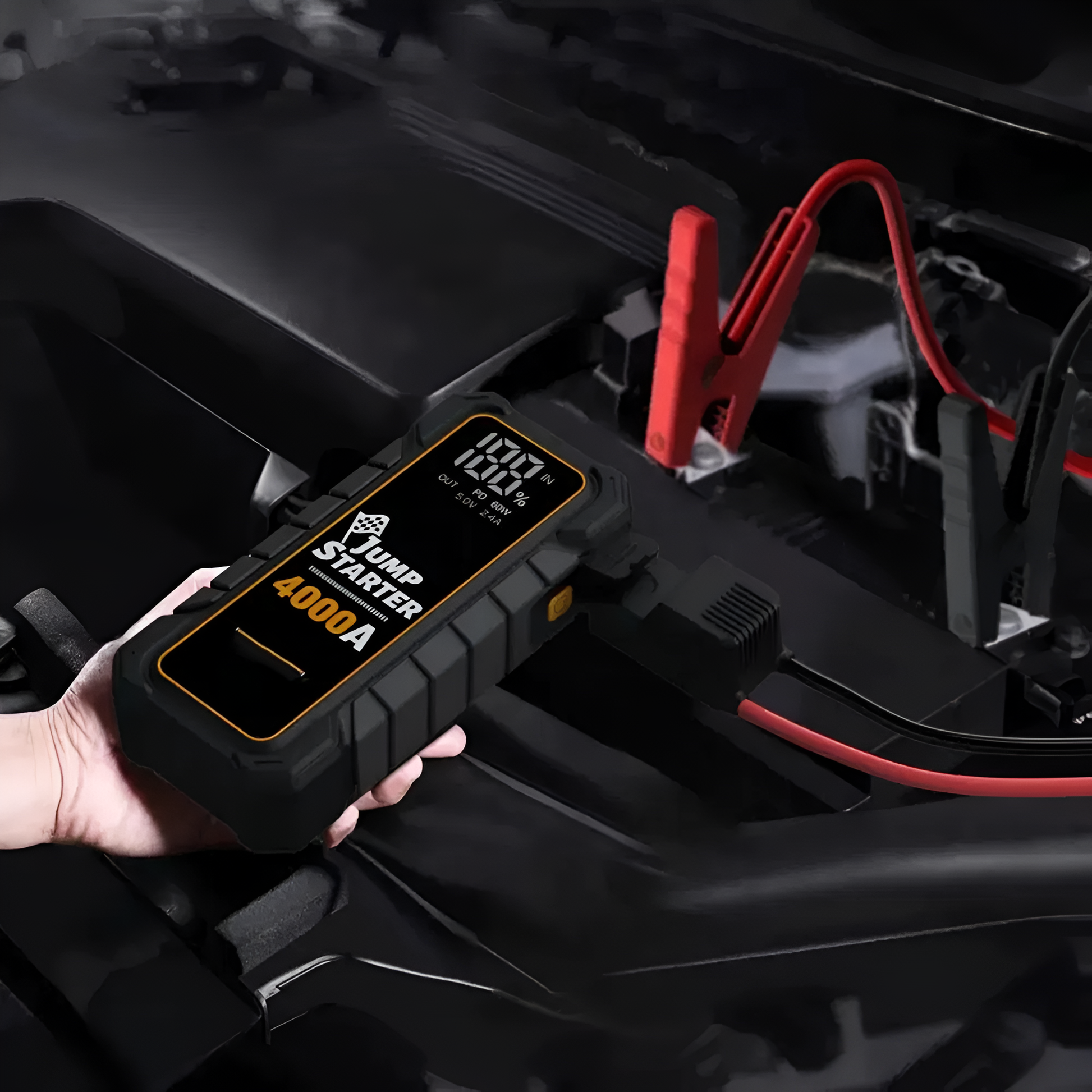 Car jump starter being used to charge a car battery with visible branding.