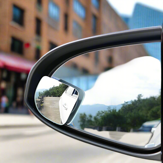 Car side mirror with a small additional mirror attached to it.