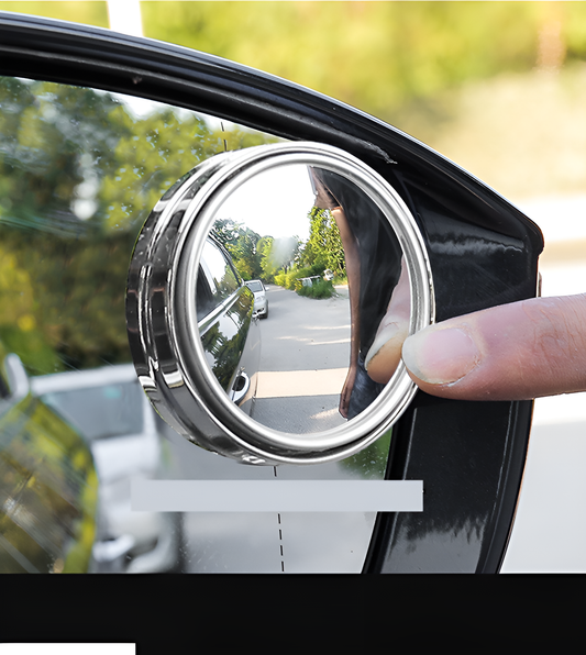 Car side mirror with a round convex mirror attached, showing a wider view of the road.